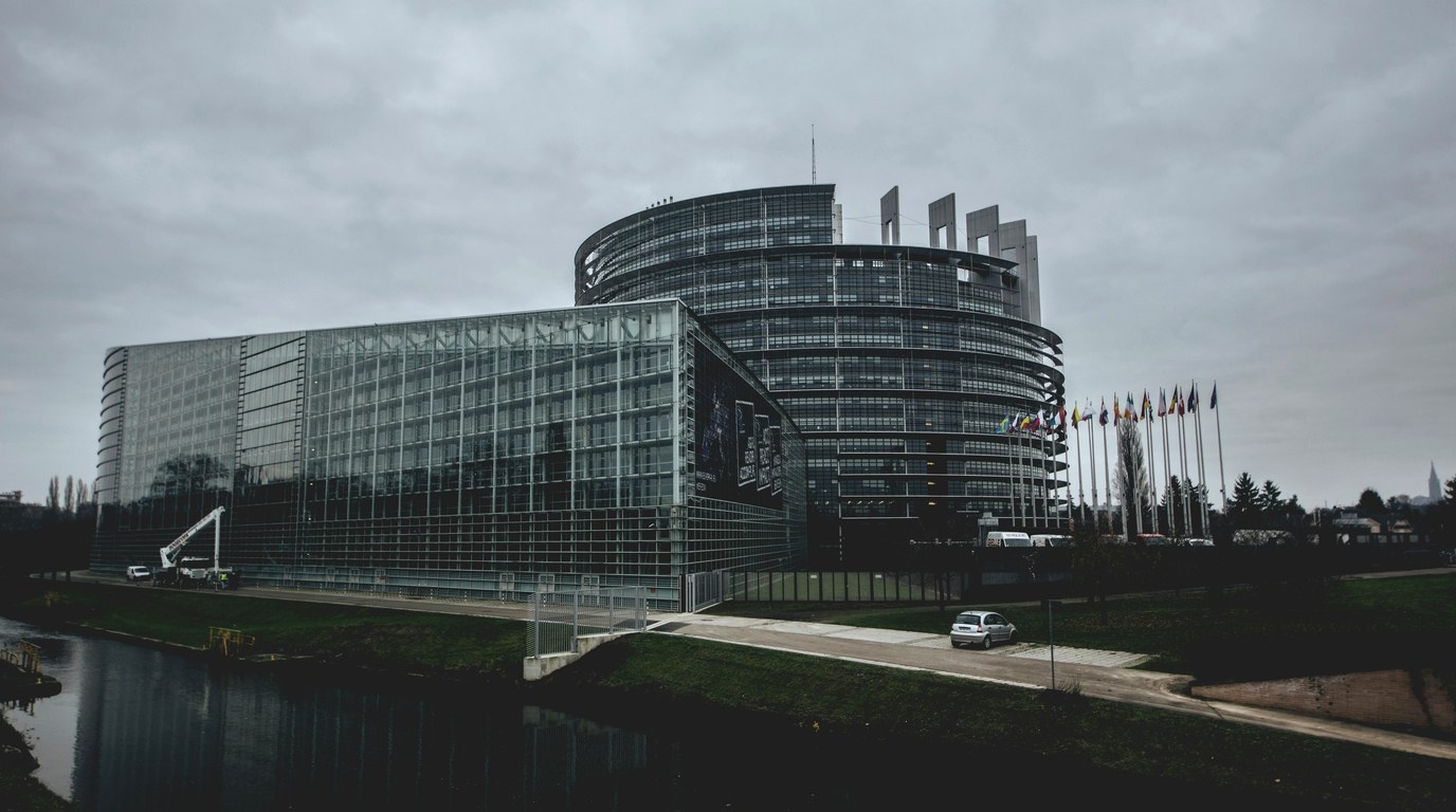 Gebäude des Europäischen Parlaments mit wehenden EU-Flaggen, Symbolbild für EU AI Act und Digital Omnibus