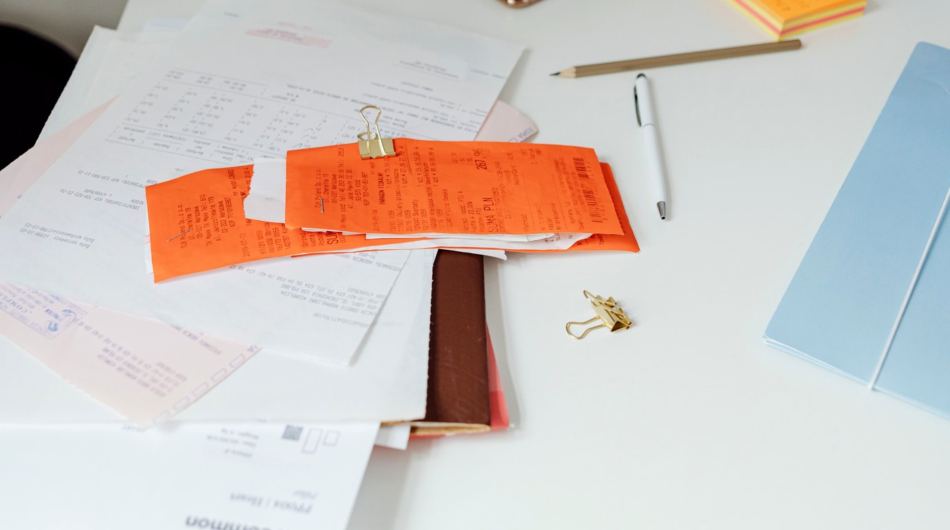 Quittungen und Dokumente auf einem Schreibtisch, daneben ein Notizbuch