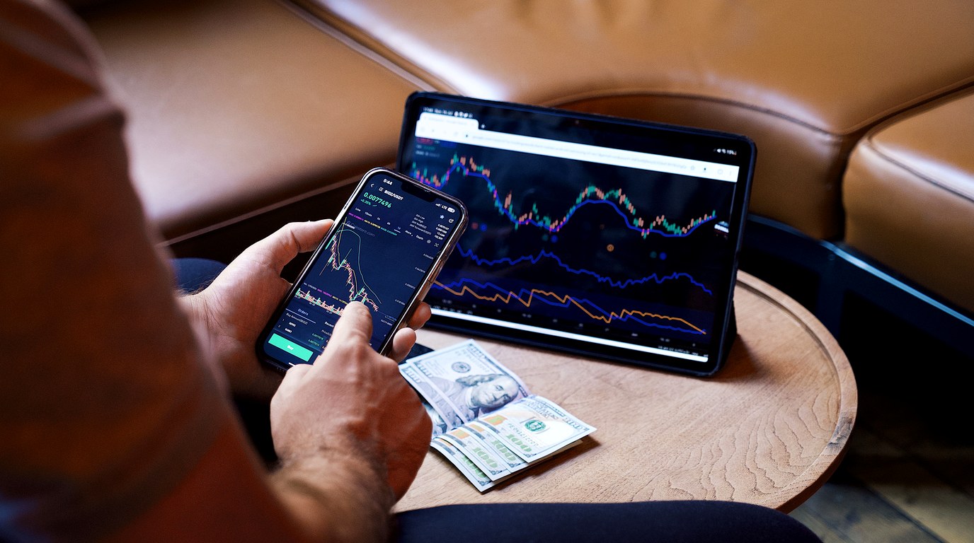 Mann schaut auf Daten-Diagramme auf Smartphone und Tablet, mobile Analyse am Schreibtisch