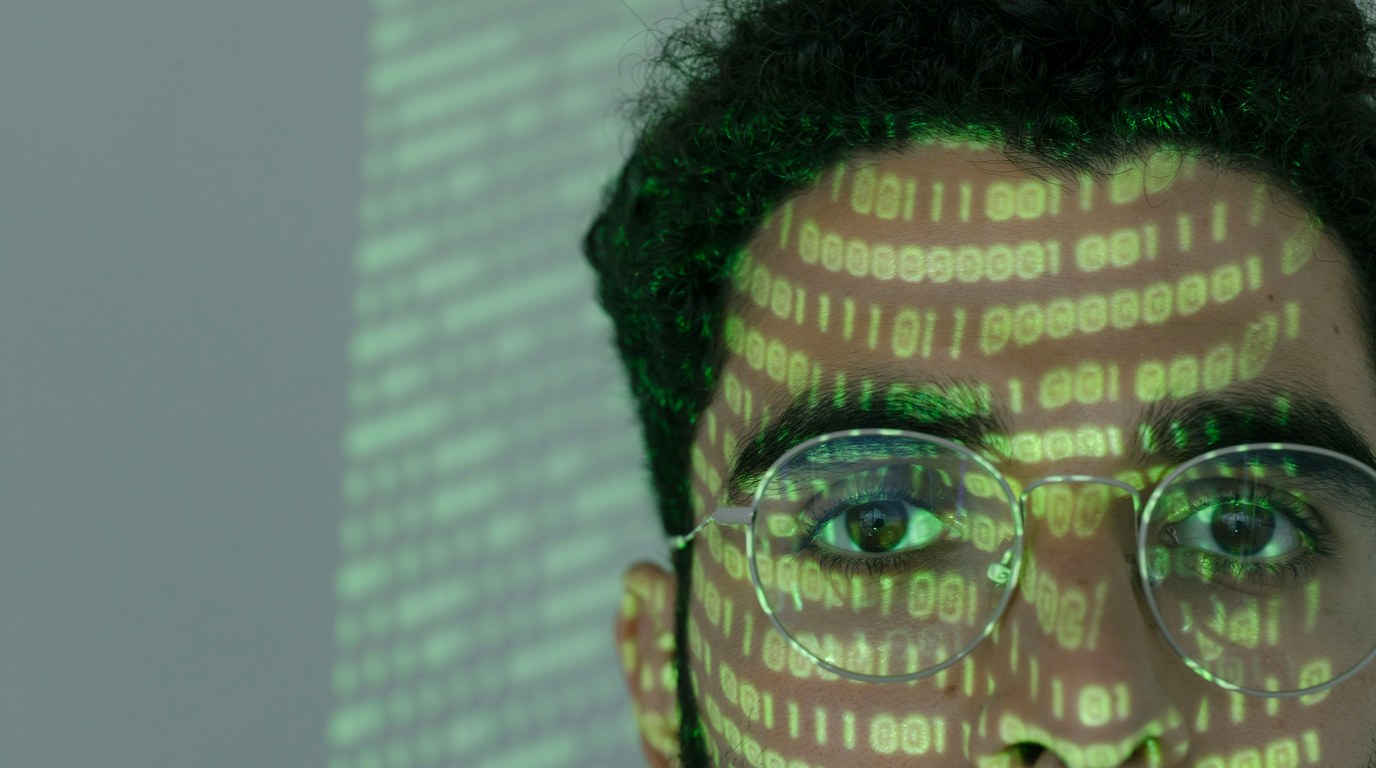 Person am Schreibtisch prüft Unterlagen und Laptop, Datenschutz-Compliance im Büroalltag
