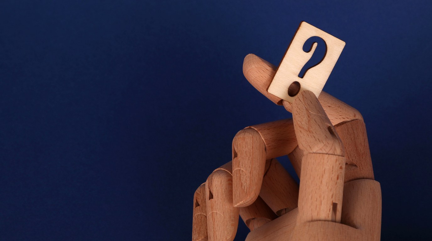 Holzhand haelt ein Fragezeichen, Symbol fuer die Frage nach dem richtigen KI-Tool