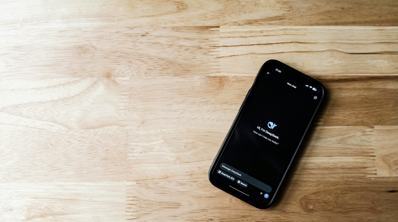 Smartphone mit geöffnetem Chat-Interface liegt auf einem Holztisch