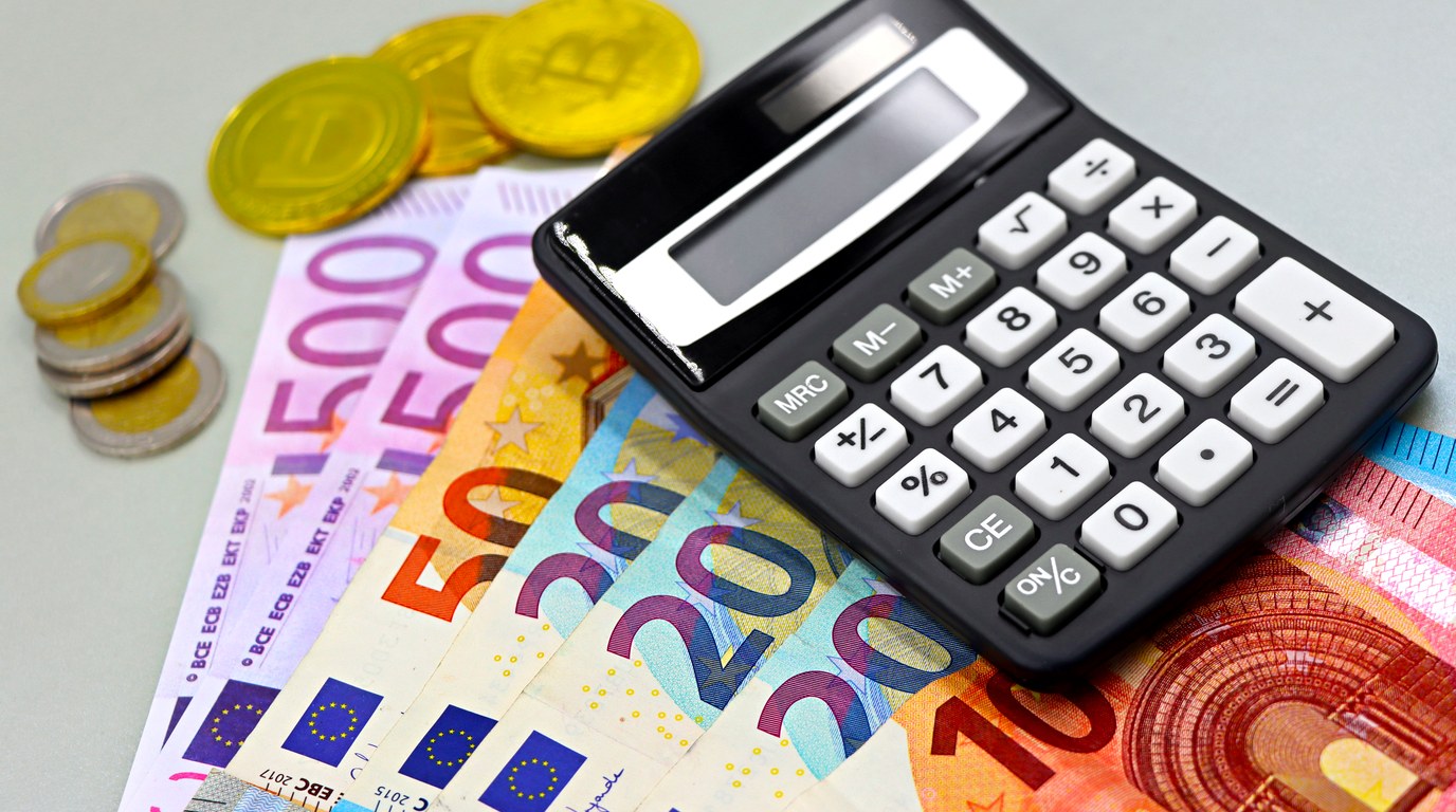 Taschenrechner auf Euro-Banknoten und Münzen bei einer Kostenkalkulation
