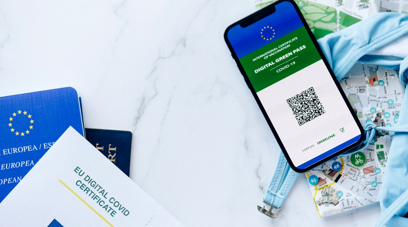 Reisepaesse und ein digitales Zertifikat neben einem Smartphone mit QR-Code auf einer Marmorflaeche