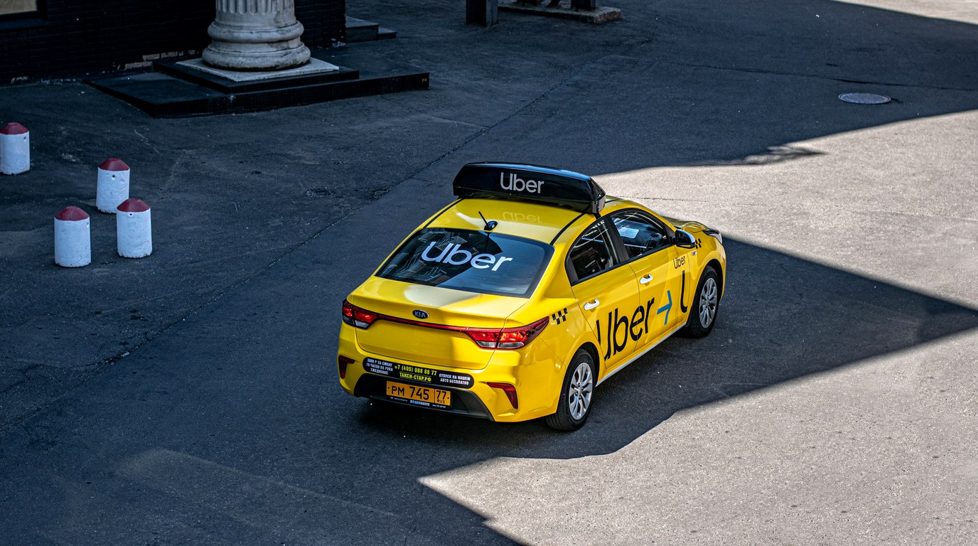 Gelbes Uber-Taxi von oben fotografiert auf einer Stadtstraße