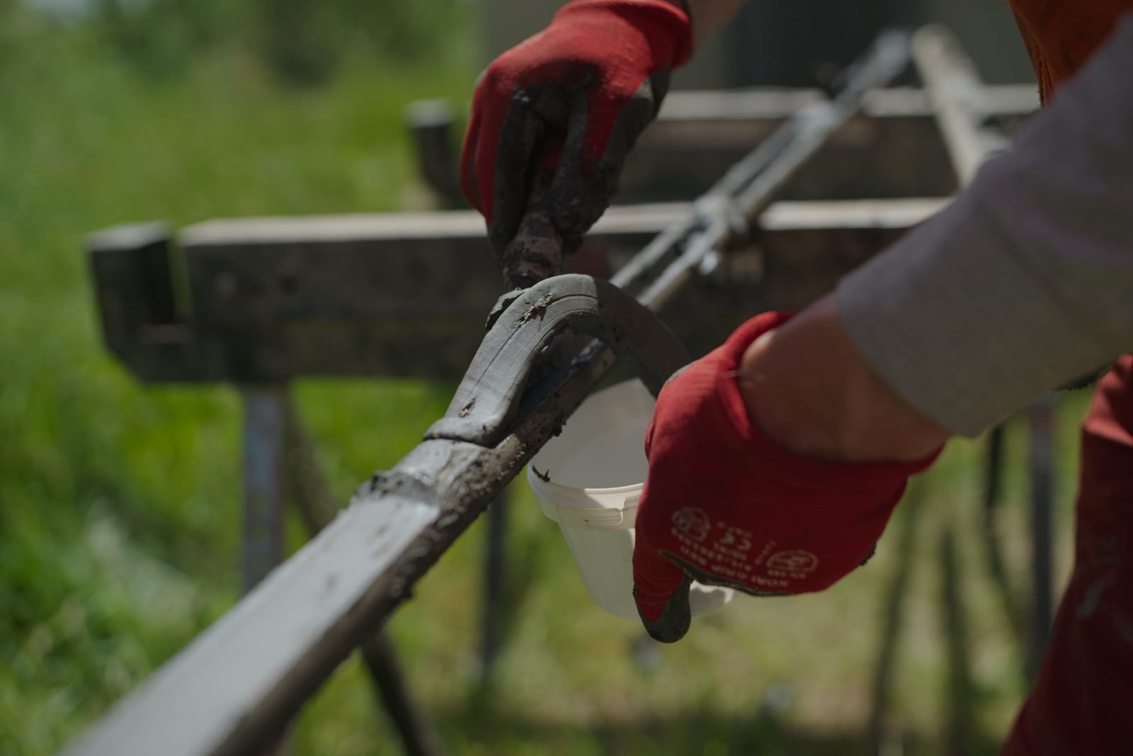 Hände in roten Arbeitshandschuhen entnehmen eine frische Bodenprobe aus dem Bohrgestänge