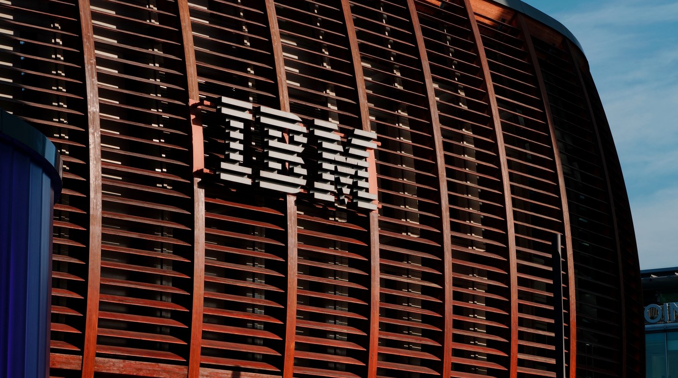 Geschwungene Gebäudefassade mit horizontalen Holzlamellen und großem IBM-Logo im Abendlicht