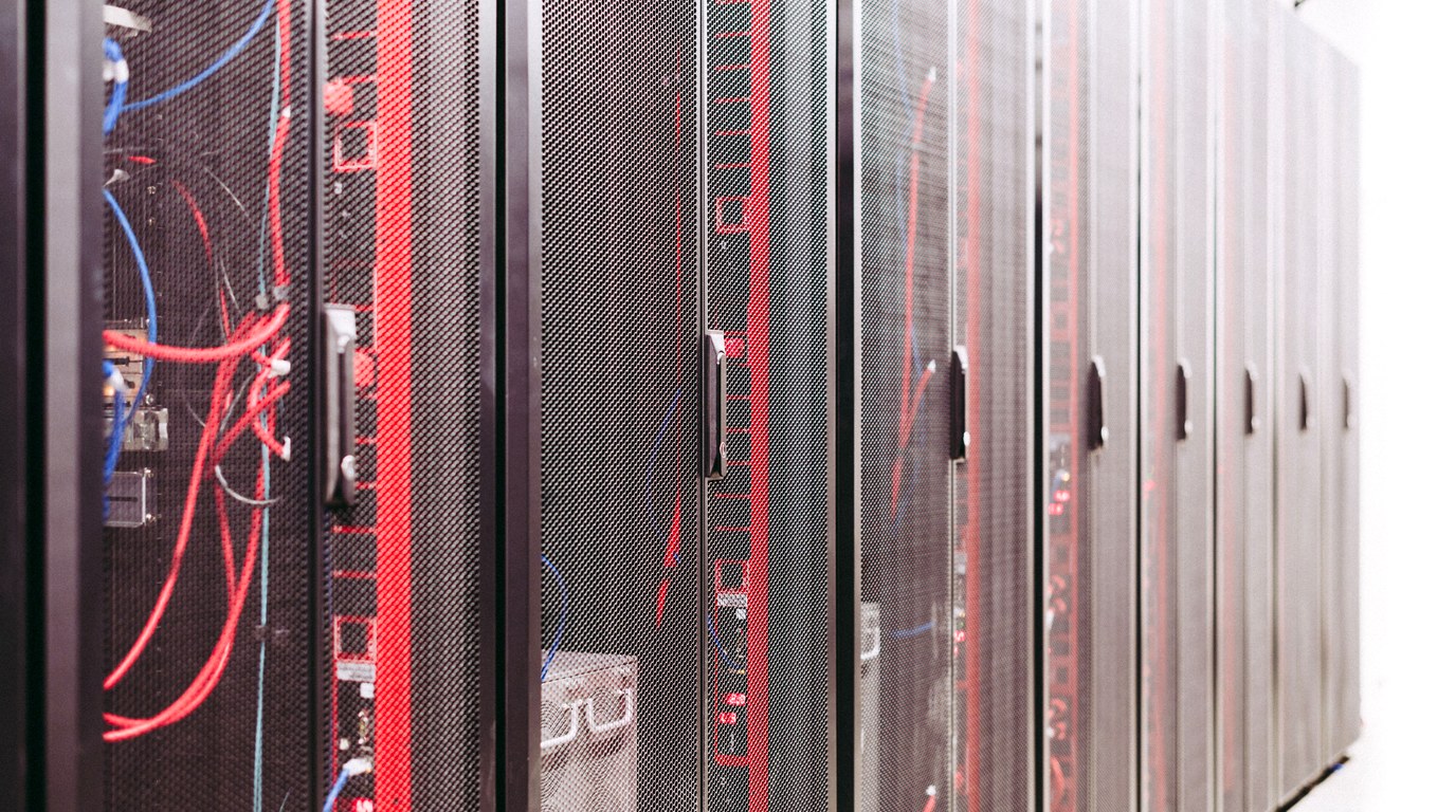 Reihe schwarzer Serverschränke im Rechenzentrum, rote und blaue Netzwerkkabel hinter den Gittertüren